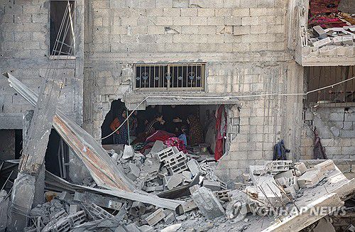 가자지구 라파에서 공습으로 무너진 건물에 팔레스타인인들이 앉아 있다. [EPA=연합뉴스]