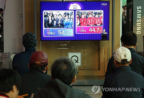 '부산 북구갑 출구조사'(서울=연합뉴스) 김성민 기자 = 제22대 국회의원선거일인 10일 오후 서울 중구 서울역에서 시민들이 더불어민주당 전재수 후보와 국민의힘 서병수 후보가 출마한 부산 북 갑 출구조사 관련 방송을 지켜보고 있다. 2024.4.10 ksm7976@yna.co.kr