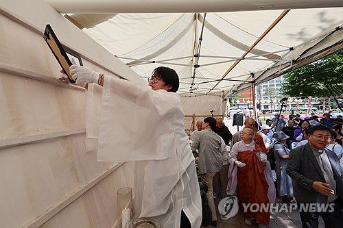 내려지는 영정(서울=연합뉴스) 신현우 기자 = 16일 오후 서울광장에 마련된 10·29 이태원 참사 합동 분향소에서 희생자 영정이 유가족들에게 전달되고 있다.     이날 분향소는 서울광장에서 을지로1가 부림빌딩 1층 실내로 이전했다. 2024.6.16 nowwego@yna.co.kr