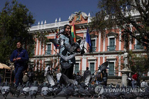 하루 만에 되찾은 평화(라파스 로이터=연합뉴스) 27일(현지시간) 볼리비아 라파스 대통령궁 앞에서 한 주민이 비둘기에게 모이를 주고 있다. 2024.6.28