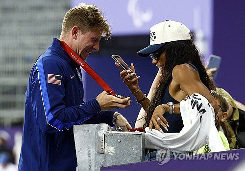 남편의 금메달을 사진으로 담는 데이비스-우드홀(파리 로이터=연합뉴스) 데이비스-우드홀이 7일(한국시간) 프랑스 파리 스타드 드 프랑스에서 열린 2024 파리 패럴림픽 육상 남자 400ｍ(T64) 결선에서 남편 우드홀의 우승한 뒤, 남편의 금메달을 사진으로 담고 있다.