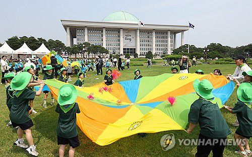 국회 찾은 어린이들 '한마음으로'지난 6월 10일 국회에서 산림청이 주최하고 한국숲유치원협회가 주관해 열린 제3회 대한민국 유아숲 교육대회를 찾은 어린이와 교사들이 낙하산 모양의 대형 천위에 제기를 올려 공중에 띄우는 '파라슈트' 놀이를 즐기고 있다. [연합뉴스 자료사진. 재판매 및 DB 금지]