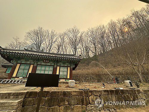 사찰 인근에 물 뿌리는 대전사(청송=연합뉴스) 강태현 기자 = 26일 오전 경북 청송 주왕산 국립공원의 '얼굴' 천년고찰 대전사가 희뿌연 연기에 뒤덮여 있는 가운데 사찰 관계자들이 곳곳에 물을  뿌리고 있다.     지난 22일 의성에서 시작해 닷새째 확산 중인 산불이 전날 안동을 지나 청송 주왕산 국립공원까지 번지면서 밤사이 대전사에도 비상이 걸렸으나 불길이 옮겨붙지는 않았다. 2025.3.26 taetae@yna.co.kr