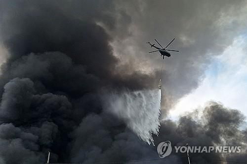 샤히드라자이 항구 상공 날며 진화하는 소방헬기[AFP=연합뉴스. 재판매 및 DB 금지]