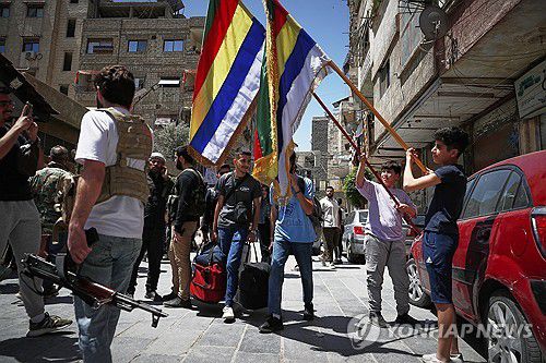 충돌 벌어진 드루즈 마을(자라마나 AP=연합뉴스) 29일(현지시간) 시리아 수도 다마스쿠스 외곽 자라마나 마을의 아이들이 드루즈교를 상징하는 깃발을 들고 있다. 2025.4.29 photo@yna.co.kr