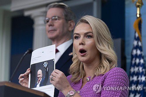 29일(현지시간) 제프 베이조스 아마존 창업자 사진이 첨부된 로이터 기사 내용 들어 보이는 캐롤라인 레빗 백악관 대변인 [AP=연합뉴스. 재판매 및 DB 금지]