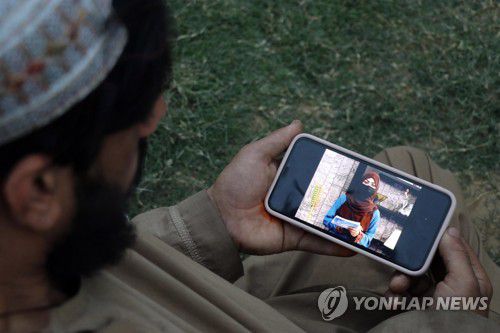 얼굴을 가린 여성 앵커의 뉴스 진행 장면을 보는 아프간 남성[EPA 연합뉴스 자료사진. 재판매 및 DB 금지]