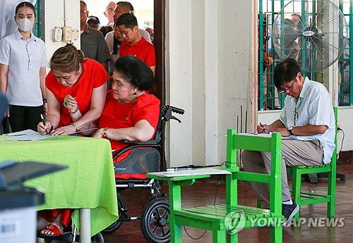 PHILIPPINES-VOTE(일로코스노르테[필리핀] AFP=연합뉴스) 페르디난드 마르코스 필리핀 대통령(오른쪽)과 휠체어에 앉은 모친 이멜다 마르코스가 12일(현지시간) 필리핀 북부 루손섬 일로코스노르테주의 투표소에서 투표하고 있다. 2025.05.12