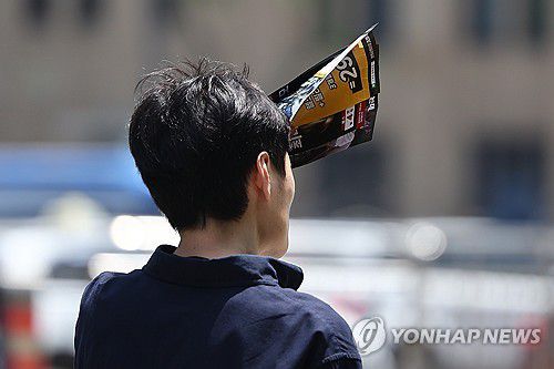 광화문에서 한 시민이 전단지로 햇빛을 가리고 있다. [연합뉴스 자료사진]