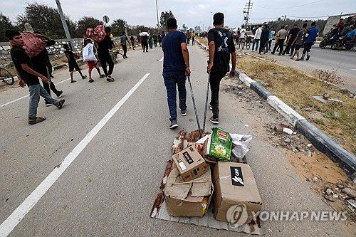 구호품 가져가는 팔레스타인 주민들(가자지구 AFP=연합뉴스) 8일(현지시간) 가자지구 중부 지역에서 주민들이 GHF가 배급한 구호품을 가져가고 있다. 2025.06.11