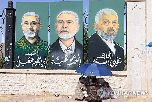 예멘에서 열린 후티 지지 집회 현장 근처에 걸려있는 하마스 지도부 초상화(사나 EPA=연합뉴수) 13일(현지시간) 예멘 사나에서 후티 지지자와 아이들이 거리에 걸린 하마스 지도부의 초상화 사진 앞에서 휴식을 취하고 있다. 2025.06.15