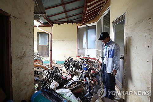 망연자실(예산=연합뉴스) 한종구 기자 = 18일 오전 충남 예산군 삽교읍 하포리 폭우 피해 현장에서 주민이 아수라장으로 변한 집안을 바라보며 한숨짓고 있다. 2025.7.18. jkhan@yna.co.kr