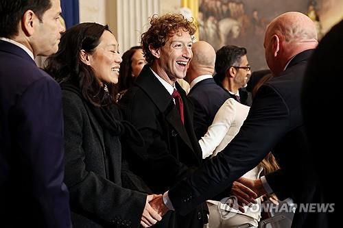 트럼프 2기 취임식 참석해 활짝 웃는 저커버그 부부[워싱턴DC UPI=연합뉴스) 2025년 1월 20일 미국 수도 워싱턴DC 소재 연방의회 의사당에서 열리는 도널드 트럼프 제47대 미국 대통령의 취임식에 참석하기 위해 도착한 마크 저커버그(사진 가운데) 메타 창립자와 그의 부인 프리실라 챈(가운데 왼쪽)이 활짝 웃으며 다른 참석자들과 인사를 나누고 있다. 2025.7.22.