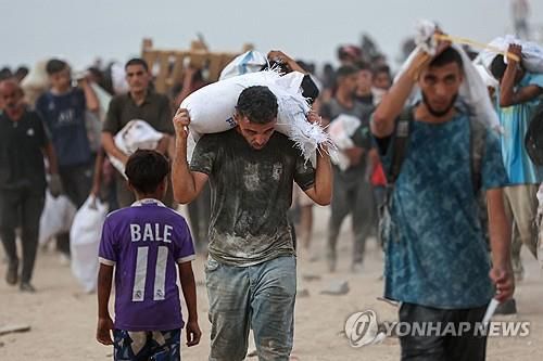 구호품 들고 가는 가자 주민[AFP=연합뉴스. 재판매 및 DB 금지]
