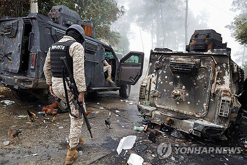 4일(현지시간) 불에 탄 경찰차량 인근 지나가는 아이티 경찰[켄스코프 로이터=연합뉴스. 재판매 및 DB 금지]