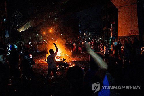 지난 9월 21일 필리핀 마닐라에서 열린 시위 도중 참가자들이 불타는 오토바이 앞에서 주먹을 치켜들고 있다.[로이터=연합뉴스. 재판매 및 DB 금지]