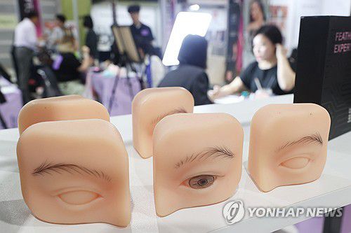 눈썹 반영구 화장9월 15일 서울 강남구 SETEC에서 열린 'PTS문신 산업 박람회'(뷰티타투페어)에서 참관객들이 눈썹 반영구 화장에 대해 설명을 듣고 있다.[연합뉴스 자료사진]