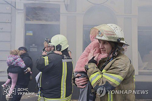 지난 22일(현지시간) 구조대원과 시민들이 러시아의 드론 공격을 받은 우크라이나 하르키우의 한 유치원에서 구조한 아이를 끌어안고 탈출하고 있다. 우크라이나 국가비상사태국 제공 사진. [AP=연합뉴스. 재판매 및 DB 금지]
