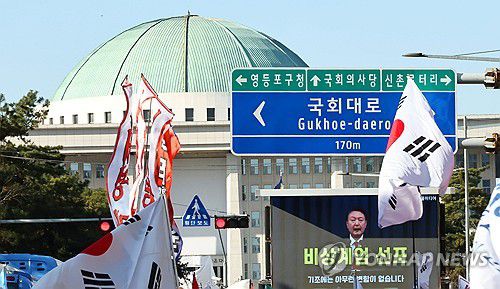 12ㆍ3 비상계엄 1주년, 국회 앞에서 재생되는 비상계엄 선포 영상(서울=연합뉴스) 김인철 기자 = 12ㆍ3 비상계엄 1주년인 3일 국회의사당역 3번 출구 앞에서 신자유연대 주최로 열린 이재명 대통령 재판 재개 촉구 집회에서 윤석열 전 대통령의 비상계엄 선포 영상이 재생되고 있다. 2025.12.3 yatoya@yna.co.kr