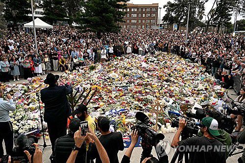 총기난사 현장의 추모객들(시드니 AFP=연합뉴스) 지난 14일(현지시간) 총기난사가 벌어진현장인 호주 시드니 본다이 비치에서 시민들이 헌화하며 희생자들을 추모하고 있다.