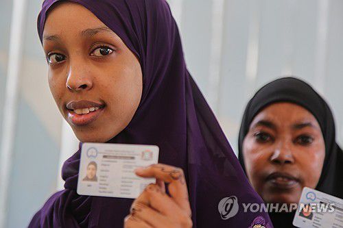 25일 소말리아 모가디슈에서 투표를 위해 선 주민들이 신분증을 보여주고 있다. [AP=연합뉴스]