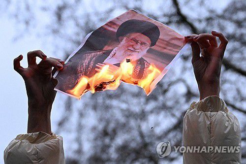 런던에서 열린 이란인 지지 시위 현장서 시위대가 하메네이 사진을 불태우고 있다.[로이터 연합뉴스 자료사진. 재판매 및 DB 금지]