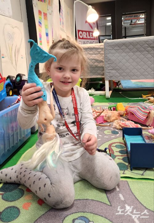 폴란드 바르샤바에 위치한 난민 캠프에서 생활하고 있는 우크라이나 아동이 장난감을 들고 밝게 웃고 있다. 최근 폴란드에선 우크라이나 아동들의 교육이 중단되지 않도록 폴란드 정규 교육 과정에 참여할 수 있도록 했다.