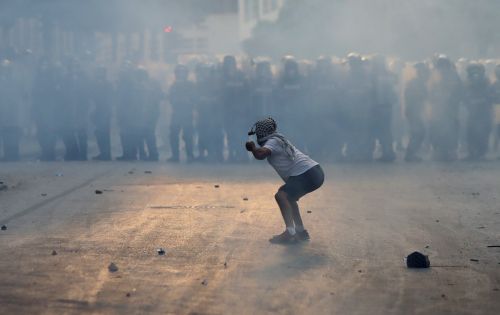레바논 베이루트에서 폭발 사고에 분노한 시민이 10일(현지시간) 반정부 시위를 벌이는 가운데 한 시위자가 경찰들에게 돌을 던지고 있다. 베이루트/로이터연합뉴스