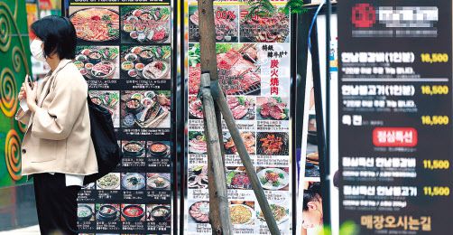 서울 중구 명동의 한 식당 안내문 앞을 시민이 지나가고 있다. [연합]