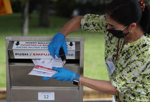 지난 19일(현지시간) 플로리다주 마이애미-데이드 카운티 지역에서 투표 업무 관계자가 우편투표 용지를 우편투표함으로 밀어넣고 있다./사진=AFP