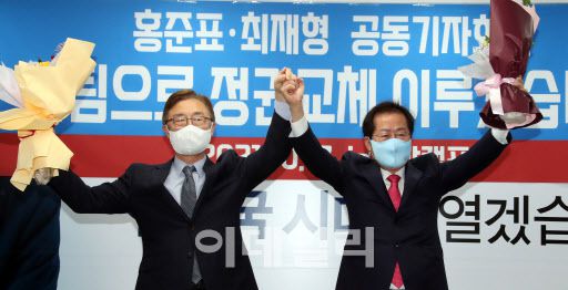 홍준표 국민의힘 대선 경선 후보(오른쪽)와 최재형 전 감사원장이  17일 오전 서울 여의도 홍 후보 캠프 사무실에서 열린 ‘최재형 전 감사원장 영입 행사 기자회견’에서 꽃을 들어 지지자들에게 인사하고 있다. (사진=연합뉴스)