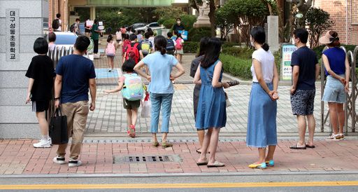 대구지역 대부분 초등학교가 여름방학을 마치고 개학한 18일 오전 대구성동초등학교 교문 앞에서 배웅 나온 학부모들이 학생들의 등교 모습을 바라보고 있다. 뉴스1