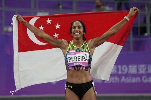 싱가포르의 베로니카 샨티 페레이라 선수가 2일 중국 항저우아시안게임 육상 여자 200m 결승에서 우승한 뒤 자국 국기를 걸치고 자축하고 있다. 항저우=AP연합뉴스