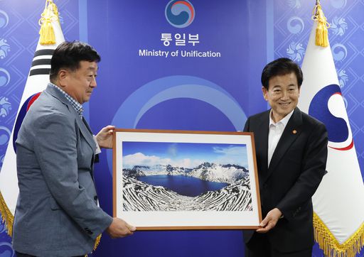 정동영 통일부 장관이 12일 서울 종로구 정부서울청사에서 열린 경협·교역·금강산 기업 단체 면담에서 앞서 참석자들과 인사하며 백두산 사진 선물을 받고 있다.    뉴시스