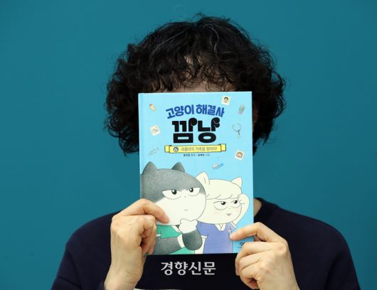 <고양이 해결사 깜냥>의 홍민정 작가가 지난달 27일 서울 정동 경향신문사 여다향에서 인터뷰 시작에 앞서 책을 들고 포즈를 취하고 있다. 서성일 선임기자