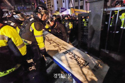 19일 새벽 서울서부지방법원 후문에서 윤석열 대통령 구속을 항의하며 법원 청사를 침입해 난동을 부린 시위대가 넘어뜨린 법원 간판을 경찰이 일으키고 있다. 2025.1.19 이준헌 기자