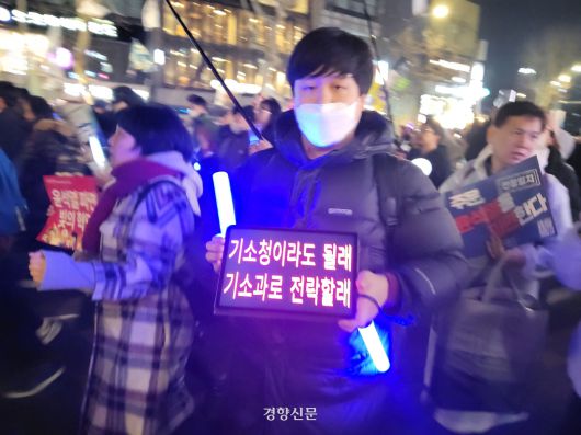 윤석열 대통령의 탄핵을 촉구하는 집회의 한 참가자가 8일 서울 종로구에서 행진하면서 미리 가지고 온 태블릿PC에 구호를 적어 선보이고 있다. 김태욱 기자