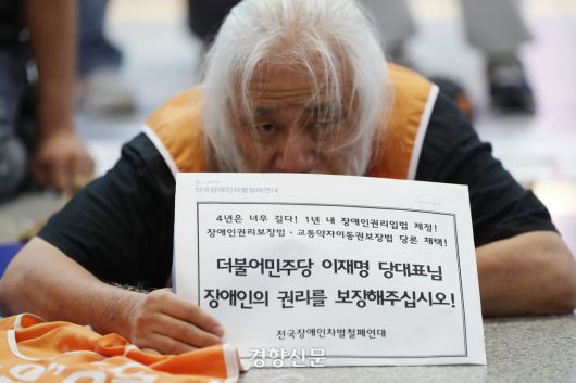 박경석 전국장애인차별철폐 연대 공동 대표가 지난 9월 서울 용산역에서 시민들에게 귀성길 인사를 하는 이재명 더불어민주당 대표에게 장애인 이동·교육·노동 등 7대 권리입법 통과를 요청하기 위한 포체투지를 하고 있다. 한수빈 기자