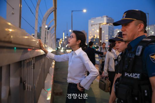 지난해 9월 10일 김건희 여사가 자살 방지를 위해 서울 마포대교 난간에 설치된 도르래를 만져보고 있다.  여사 뒤로 경호 인력이 시민 통행을 막고 있는 모습이 보인다. 대통령실 제공
