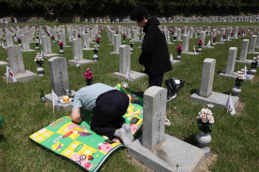 6·25전쟁 75주년을 사흘 앞둔 22일 서울 동작구 국립서울현충원 묘역에서 유족 홍인표씨가 가족들과 함께 아버지 묘지를 찾아 참배하고 있다. 성동훈 기자