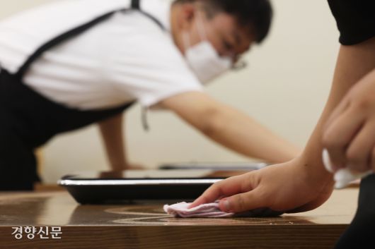 혜화 슬로우점에서 일하는 느린 학습자 청년들이 식탁을 닦고 있다.