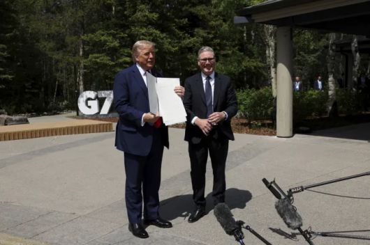 도널드 트럼프 미국 대통령(왼쪽)이 지난 6월 캐나다 앨버타주 캐내내스키스에서 키어 스타머 영국 총리와의 정상회담 후 서명한 미·영 무역협정 문서를 들어 보이고 있다. AP연합뉴스