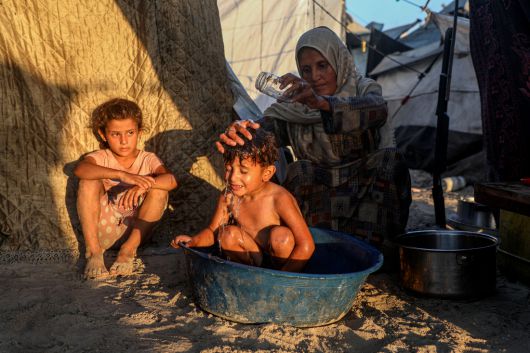 18일 (현지시간) 한 팔레스타인 어린이가 가자시티 해변에 설치된 난민 캠프 천막 사이에서 목욕을 하고 있다. 신화연합뉴스