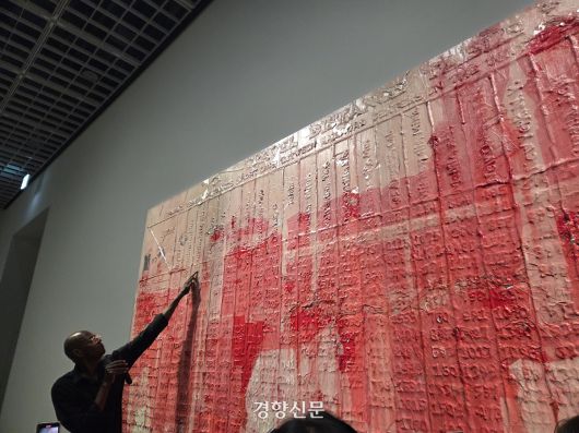 마크 브래드포드가 서울 용산구 아모레퍼시픽미술관에 전시한 기차 시간표 연작 ‘핑크 레이디’(2025) 앞에 서 작품설명을 하고 있다. 윤승민 기자