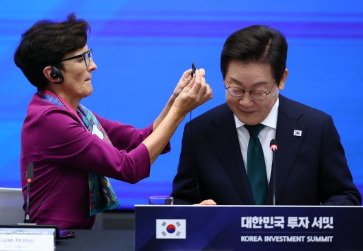 이재명 대통령이 25일(현지시간) 미국 뉴욕 증권거래소에서 열린 한국경제설명회 투자서밋에서 제인 프레이저 씨티그룹 회장의 도움을 받아 통역기를 착용하고 있다. 연합뉴스