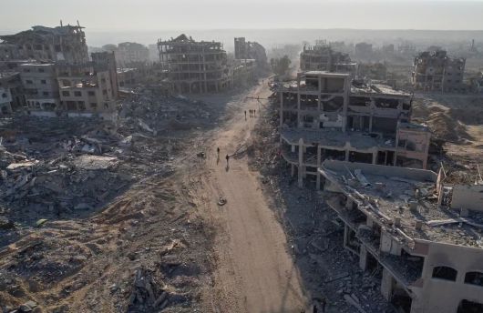 11일(현지시간) 촬영된 드론 영상에서 팔레스타인인들이 가자시티에서 파괴된 건물에 둘러싸여 걷고 있다. AP연합뉴스