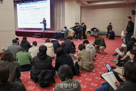 학부모들이 바닥에 앉아 설명회를 듣고 있다.