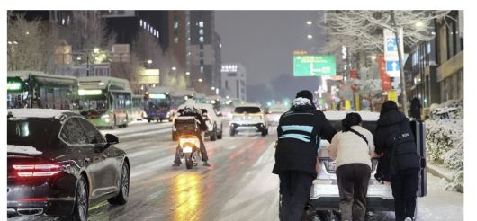 지난 4일 저녁 서울 마포구 홍대 인근에서 제설작업이 완료되지 못한 도로에서 시민들이 언덕길 차를 밀고 있다. 그 옆으로는 빙판이 된 도로 위로 차와 오토바이가 지나고 있다. 연합뉴스