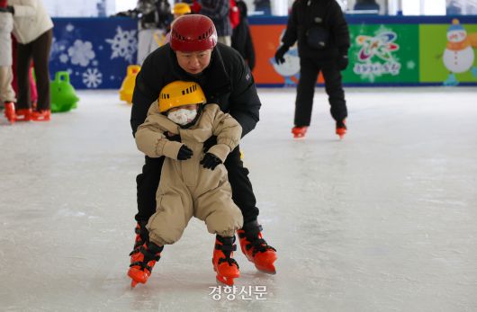 ‘노원 씽씽 눈썰매장’에 마련된 스케이트장에서 한 어린이가 아버지 품에 안겨 스케이트를 타고 있다.