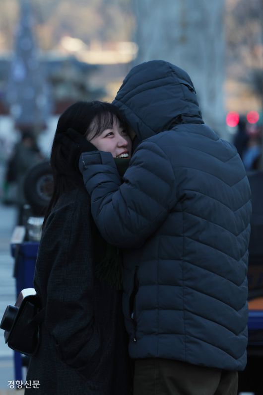 26일 서울 중구 세종대로에서 한 시민이 연인의 귀를 감싸주고 있다.